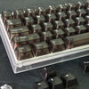 Nahaufnahme brauner und klarer getönter PC-Tastenkappen für eine mechanische Tastatur in einer hellen Metallschale.