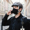A man wearing a black jacket and helmet holds a phone to his ear while carrying a tactical ID badge holder keychain.