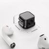 A set of magnetic cable clips shown with a white earbud, demonstrating the size and function.