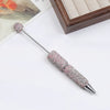 A silver pen accessory featuring a rhinestone-encrusted tip and a decorative gemstone topper.