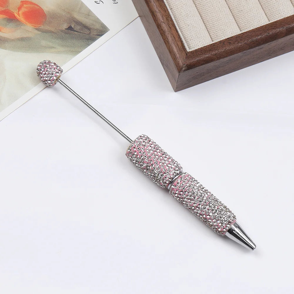 A silver pen accessory featuring a rhinestone-encrusted tip and a decorative gemstone topper.