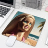 A realistic doll face featuring long brown hair and blue eyes is printed on a mouse pad.