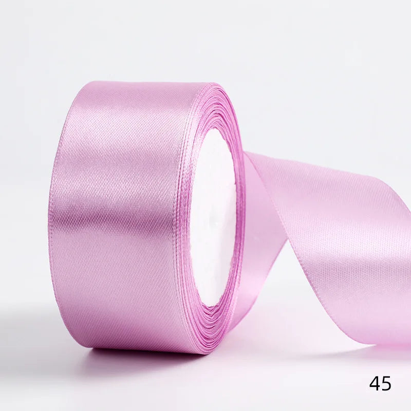 A roll of light pink satin ribbon used for gift wrapping and DIY crafts.