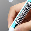 A hand holds a white permanent paint marker pen with blue accents, showing the tip and text.