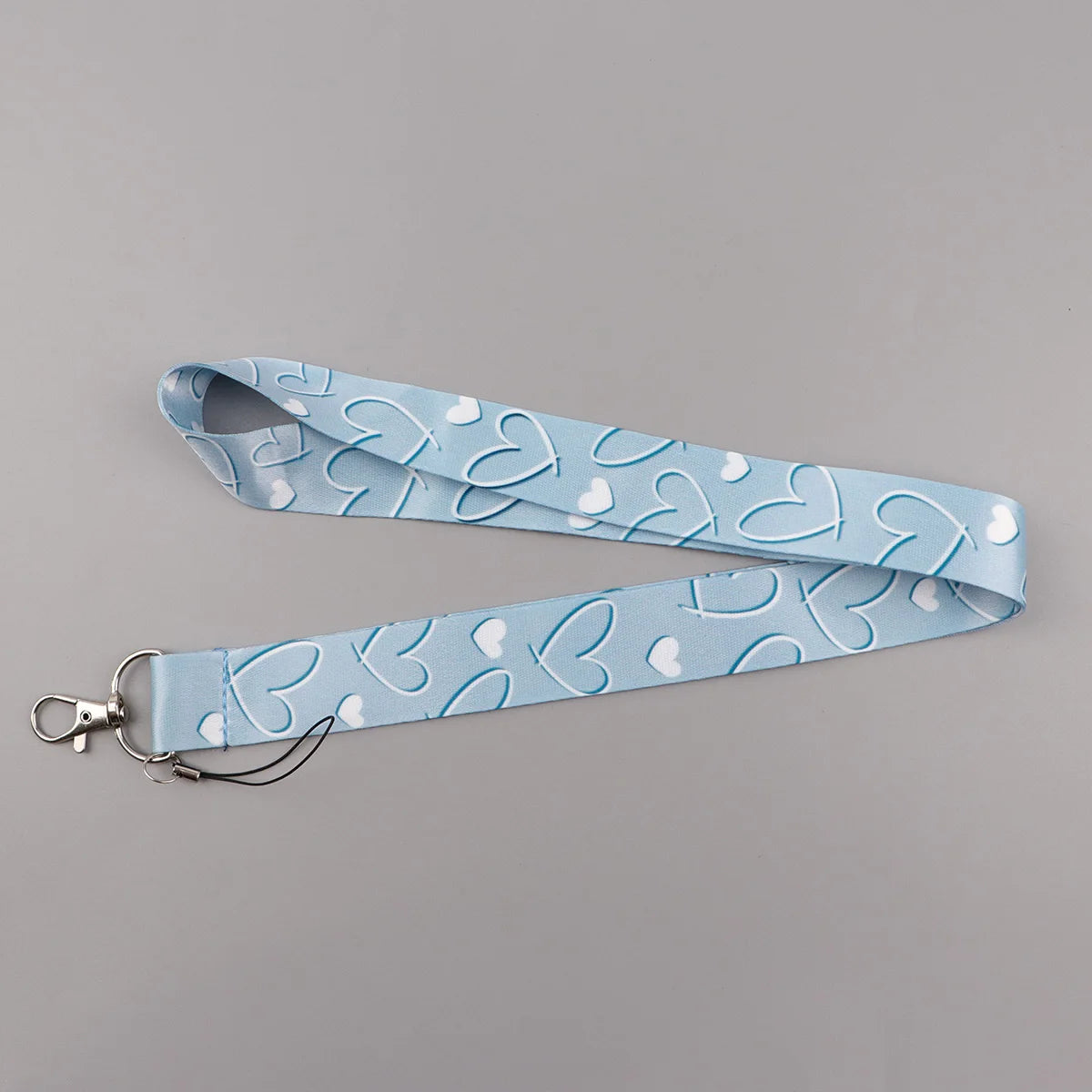 Light blue fabric lanyard with a repeating pattern of white heart shapes