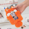 An orange plush cat photocard holder with a white soft cover is being held by a hand.