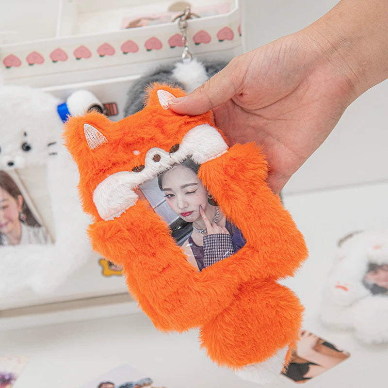 An orange plush cat photocard holder with a white soft cover is being held by a hand.
