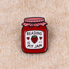 Red enamel lapel pin shaped like a jar of strawberry jam with the text Reading is my jam on the label