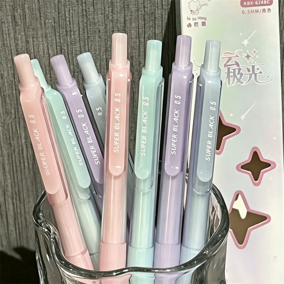 A pack of four pastel gradient gel pens in various shades of pink, purple, and blue are displayed next to their packaging.
