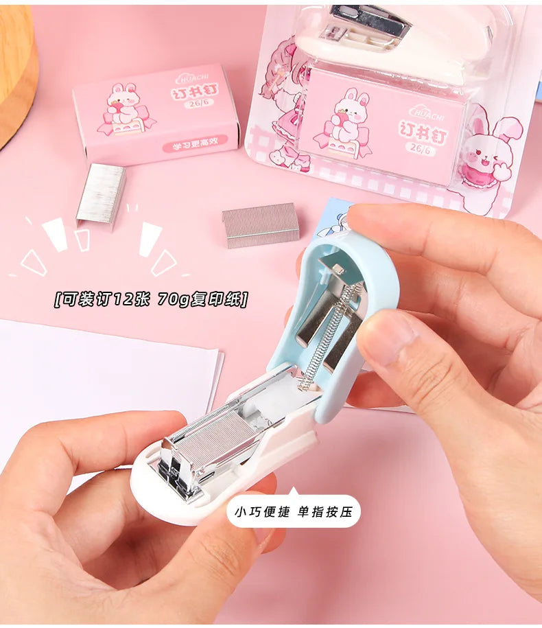 A hand holds a light blue cartoon mini stapler, demonstrating its use for stapling paper.
