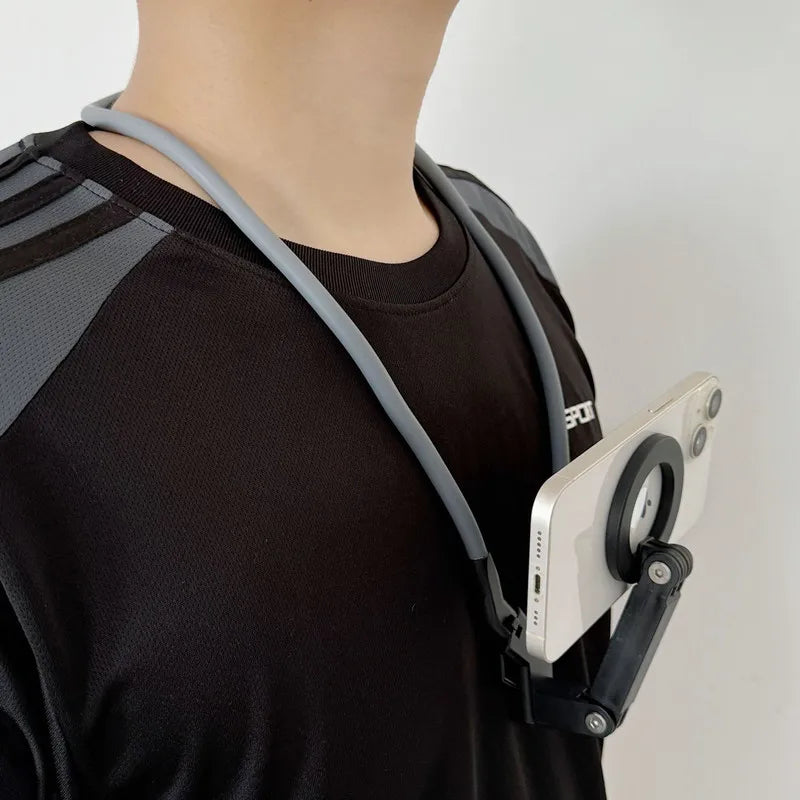 A person wearing a black shirt has a magnetic neck phone holder with a foldable tripod stand attached to their collar.
