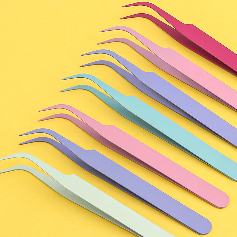 A set of pink and purple macaron precision tweezers laid diagonally on a yellow background.