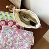 A floral quilted ladies clutch purse is shown next to a glass perfume bottle and other fabric items.