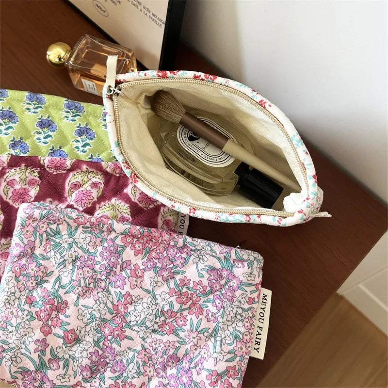 A floral quilted ladies clutch purse is shown next to a glass perfume bottle and other fabric items.