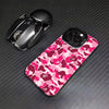 A black Apple AirPods case and a pink camouflage patterned iPhone case are displayed on a dark surface.