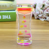 A glass hourglass filled with colorful liquid, demonstrating a sensory experience for stress relief.