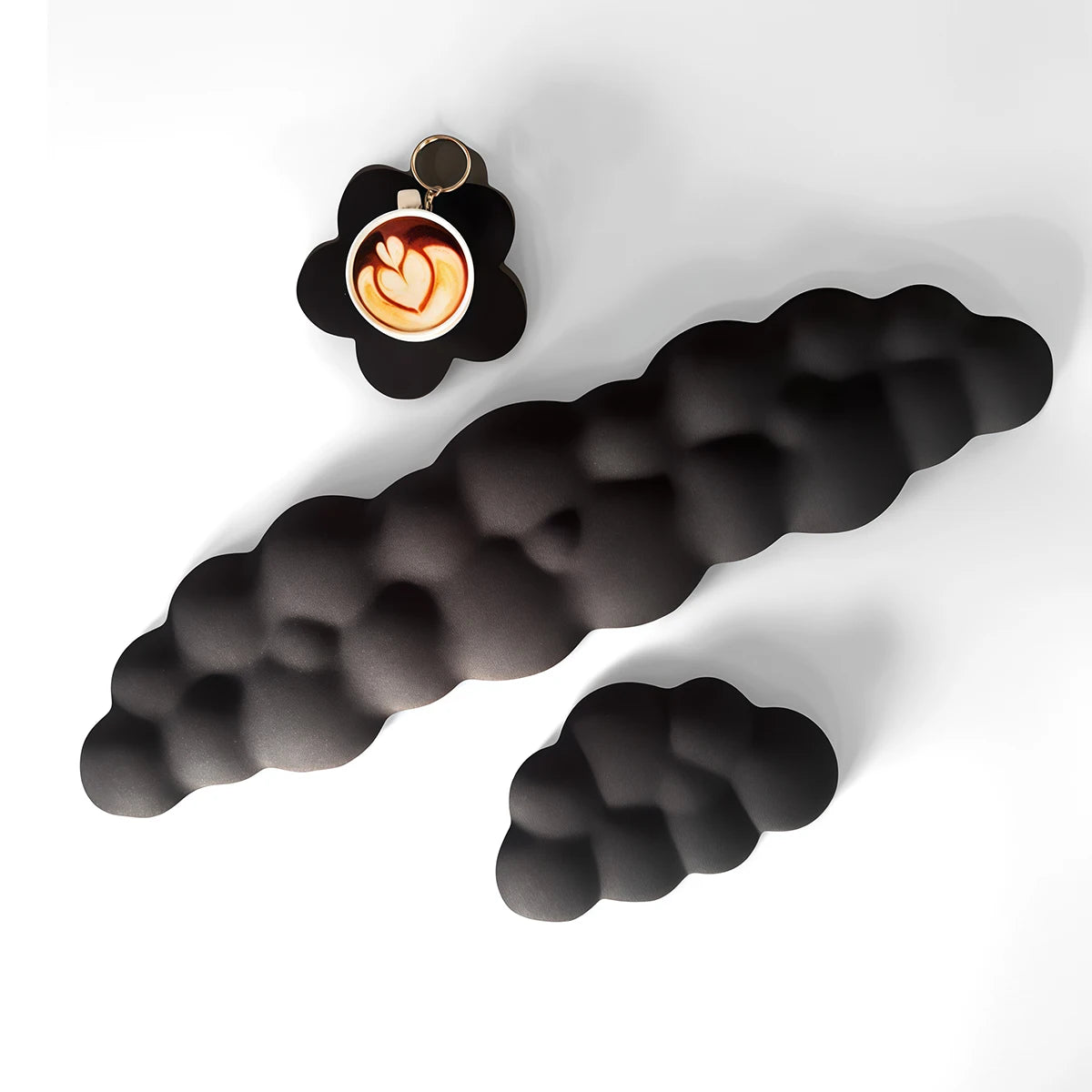 Un set de trois repose-poignets en forme de nuage noir, dont un montre une tasse à café.