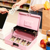 A person is placing cash into a pink secure metal money box on a white table.