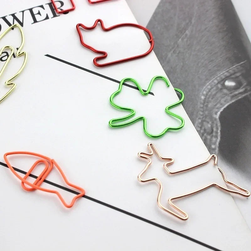 A collection of colorful decorative metal bookmarks and paper clips in various shades of red, green, and gold on a white back