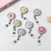A collection of floral-shaped retractable ID badge holders in pink, yellow, and purple.