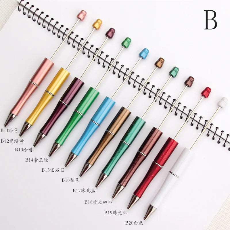 A collection of DIY beadable pens with various colored tips and black ink, arranged diagonally on a white background.