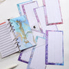 A stack of A6 budget planner binders with pink and blue marbled covers and grid paper pages.