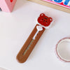 A small, orange-red cat paw shaped mini cutter with a white handle and a pink background.