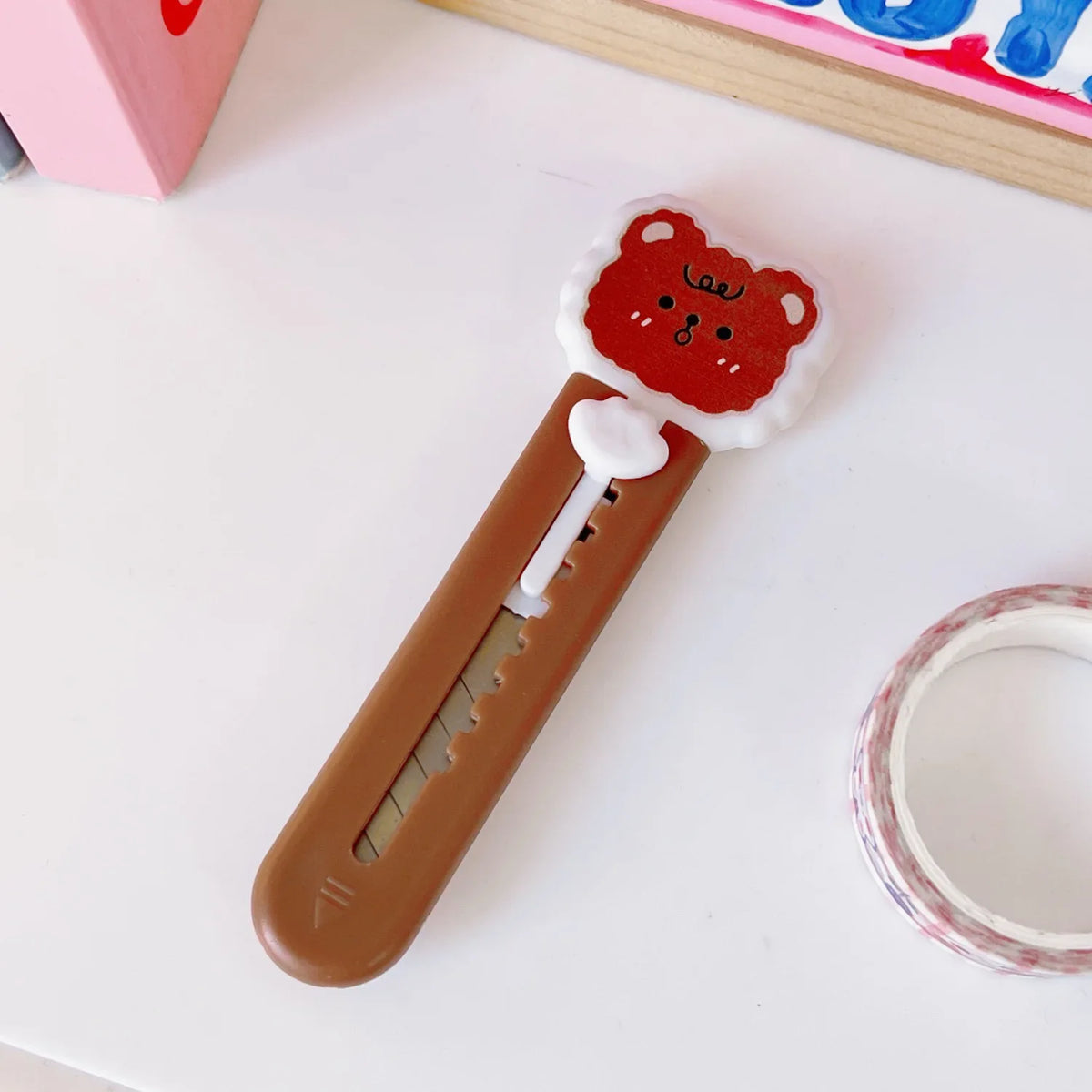 A small, orange-red cat paw shaped mini cutter with a white handle and a pink background.