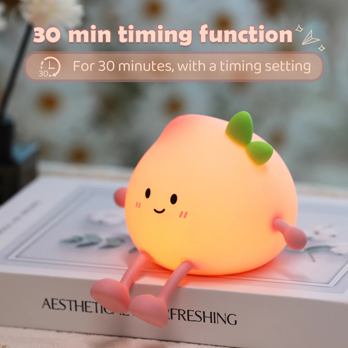 An adorable peach-shaped rechargeable night light emitting a soft orange glow on a white surface.