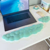 Support de poignet clavier nuage bleu sarcelle à côté d'un ordinateur portable et d'une souris sans fil sur un bureau blanc.