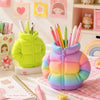 A colorful puffer jacket shaped pen holder with pastel rainbow colors sitting on a pink checkered cloth.