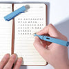 A hand writes in a notebook with a blue fountain pen, featuring Chinese calligraphy text.