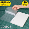 A hand holds a silver thermal laminating pouch, measuring 6R/8inch (160x225mm), on a green cutting mat.