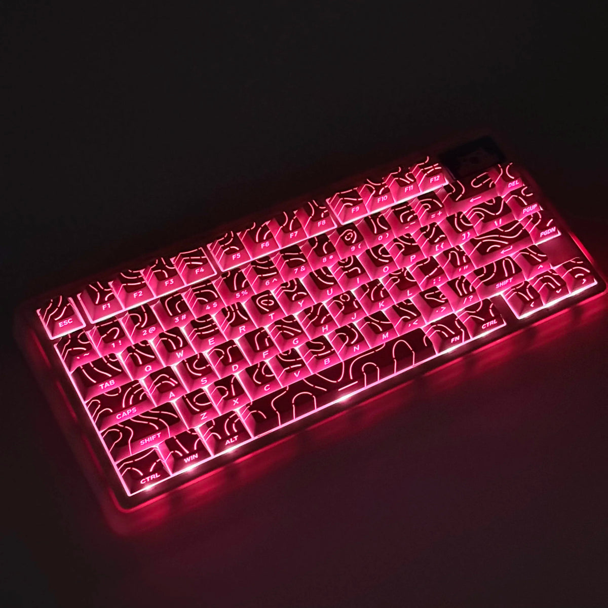 Primer plano de un teclado mecánico con teclas LED rosas y diseños de degradado intrincados iluminados contra un fondo oscuro