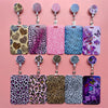 A set of purple, pink, and blue leopard print retractable card holder clips for badges and IDs.
