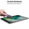 A hand is using a knife to scratch resistant tempered glass screen protector on an iPad display.