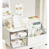 A white desktop compartment storage box with clear drawers holding various office supplies and stationery.