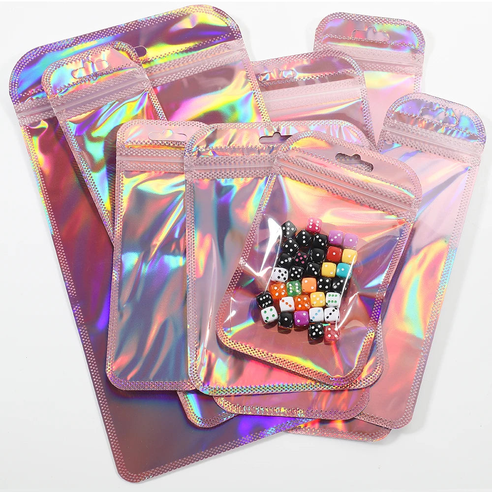 A stack of iridescent pink and purple self-sealing jewelry pouches with resealable zip locks containing a set of dice.