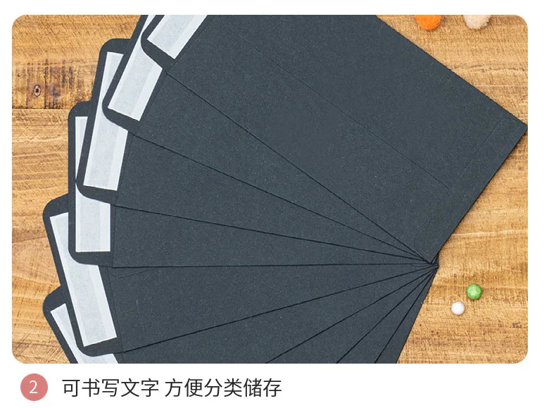 A set of black kraft envelopes is shown fanned out on a wooden surface.