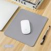 A silver portable gaming mouse pad with a white mouse and a black stylus are displayed on a wooden surface.