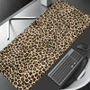 Leopard print XXL gaming mouse pad placed on a dark surface next to a computer keyboard.