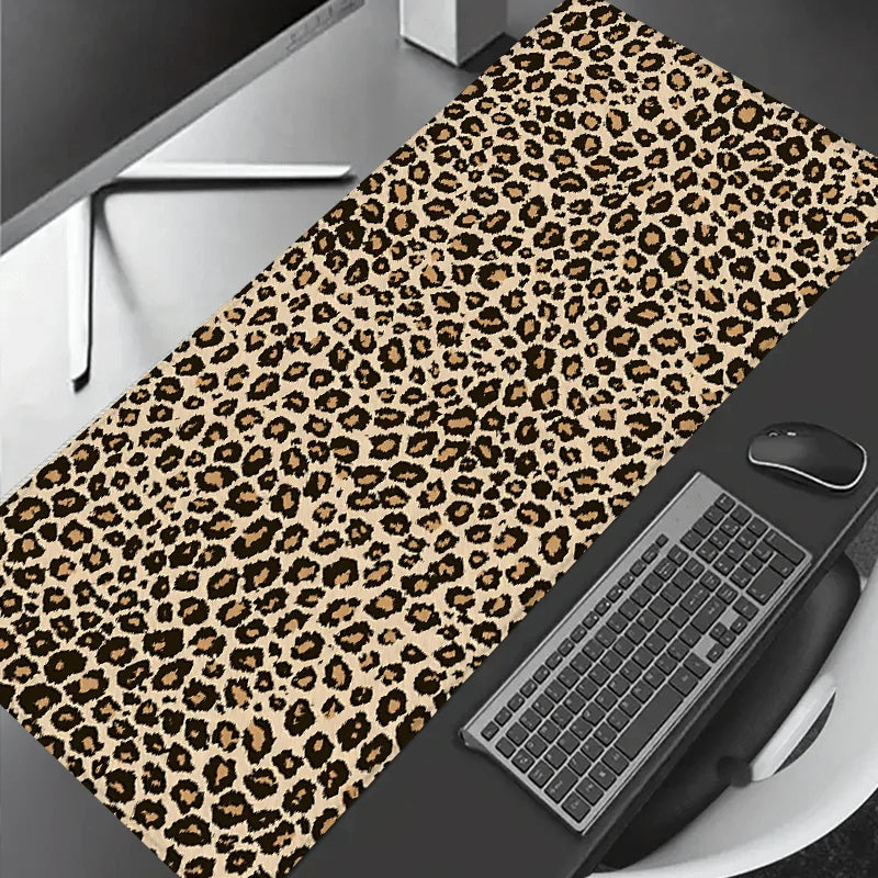 Leopard print XXL gaming mouse pad placed on a dark surface next to a computer keyboard.