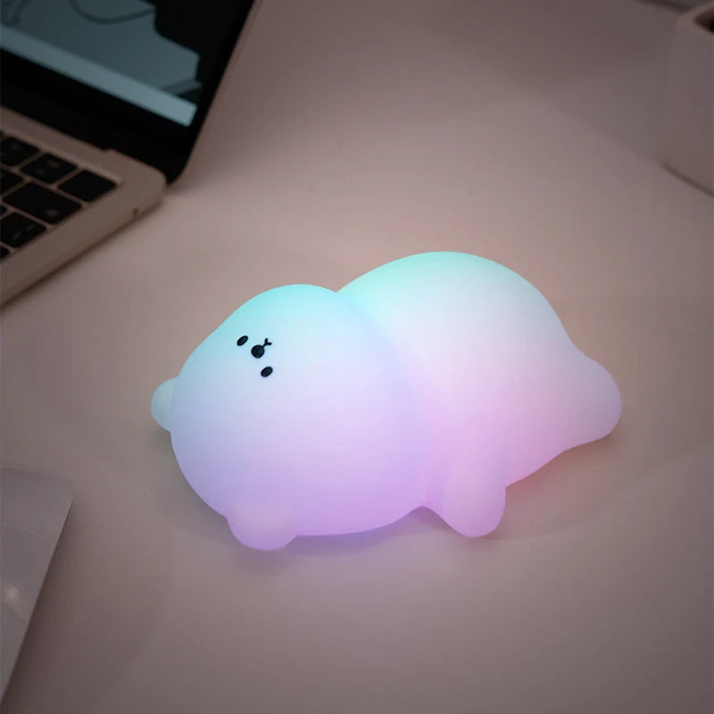 A glowing white silicone panda night light with a soft purple hue resting on a white surface.