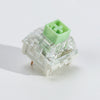 A close-up view of a light green tactile clicky mechanical keyboard switch with a clear housing and a green top cap.