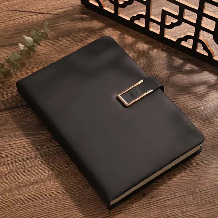 A black A5 retro leather notebook with a gold-toned clasp resting on a wooden surface.