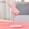 A pink rabbit-shaped mobile phone stand with a pink base shown on a table.