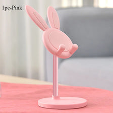 Support de téléphone en forme de lapin rose avec une base rose sur une table.