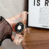 A close-up shot of a light pink resin beaded watch with a black face and gold accents, worn on a hand.
