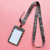 A leopard print ID holder attached to a black lanyard keychain against a pink background.