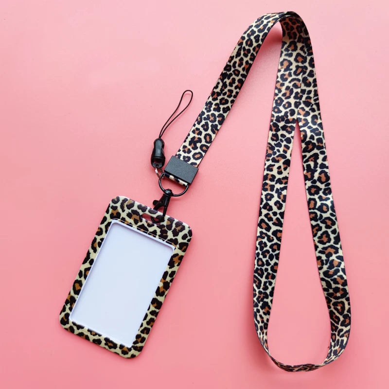 A leopard print ID holder attached to a black lanyard keychain against a pink background.